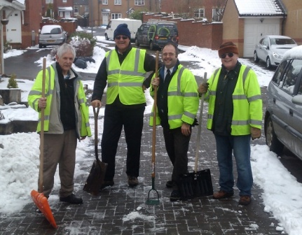 3 men in yellow viors standing in the snow with shovels in hand